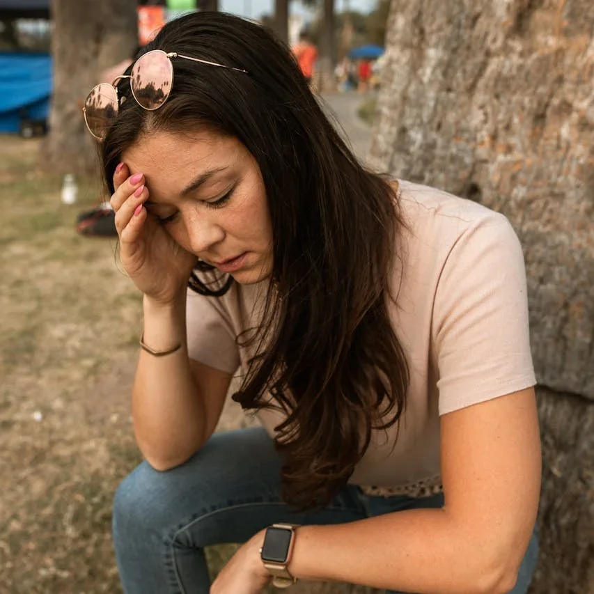 Woman crouching by wall with her head in hand