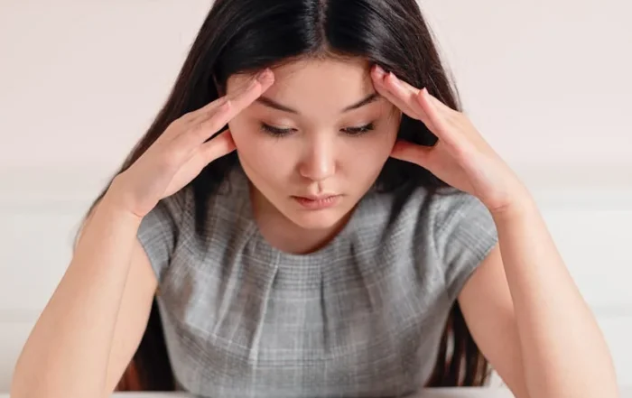 Woman sitting at desk with hands on head