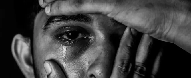 Man with hands covering face with one eye exposed