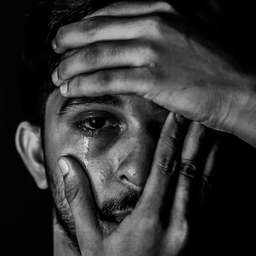 Man with hands covering face with one eye exposed