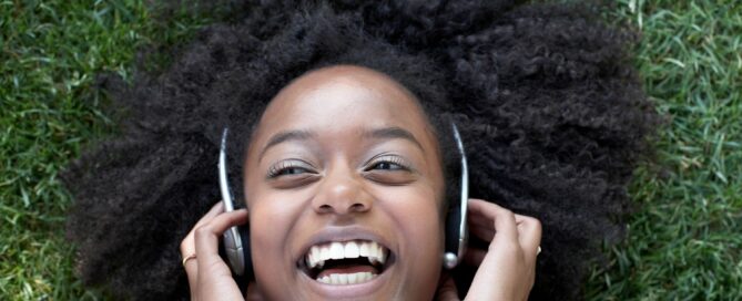 Woman laying on ground listening to headphones