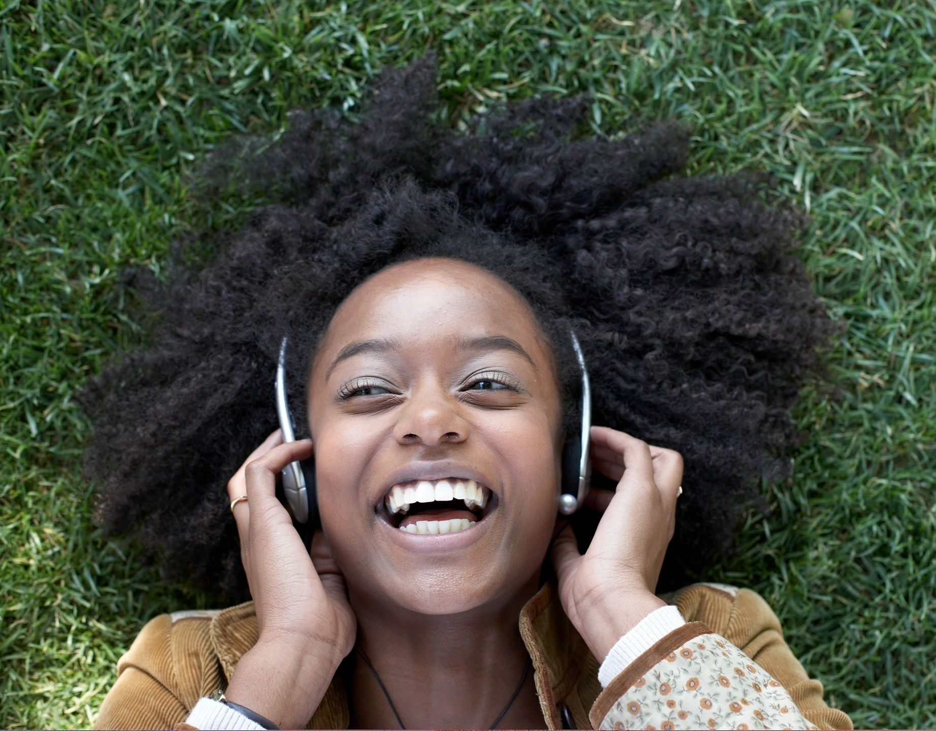 Woman laying on ground listening to headphones